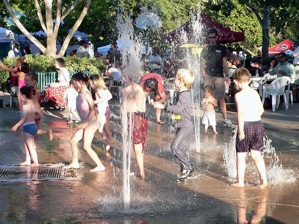 Children playing in the Central Park fountain during the Davis Farmers Market